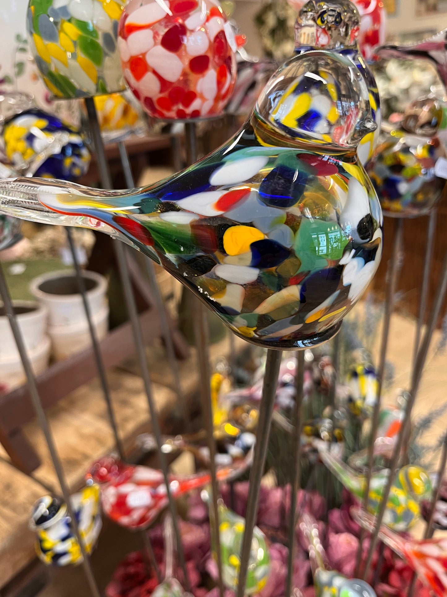 Harlekin farvet glas fugl på pind.