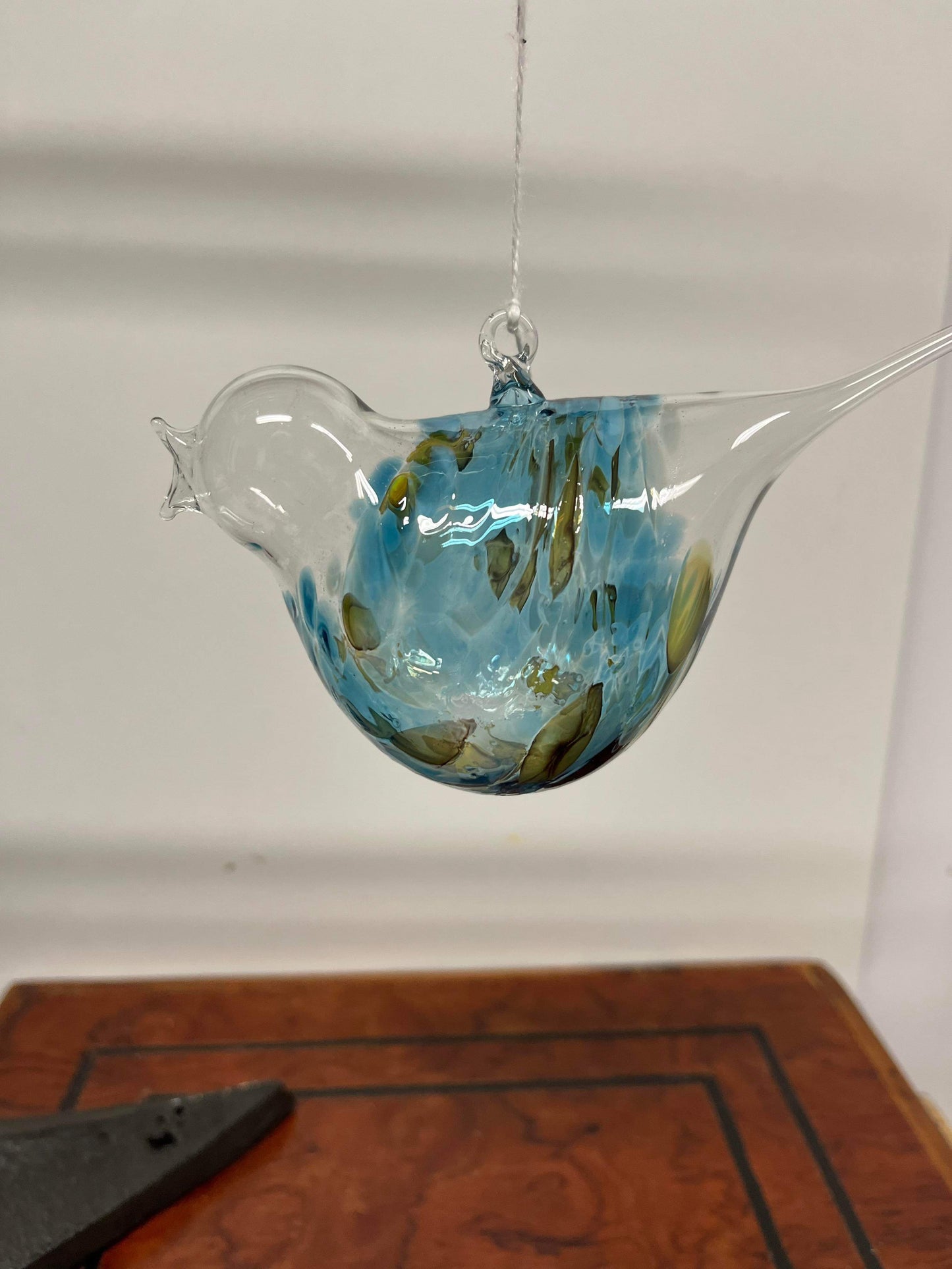 Glas fugl hængende i lys blå og grøn